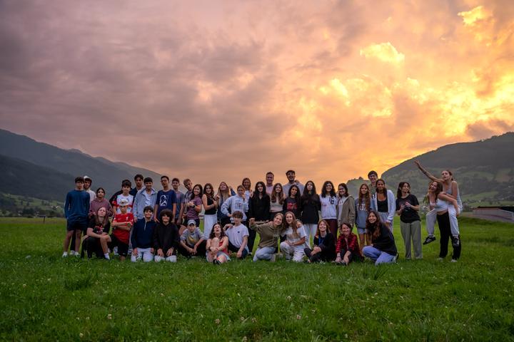 The whole camp together on the meadow at sunset, mountains behind