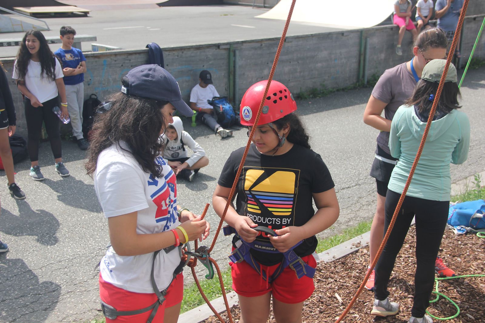 Campers in helmets getting harnessed up for climbing