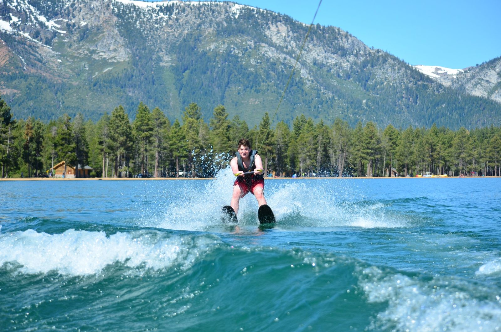 A teen waterskiing on Lake Tahoe, with snowy mountains behind