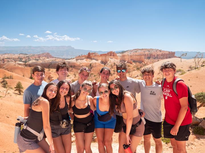 A group of teens at a lookout above the orange rock spires of Bryce Canyon