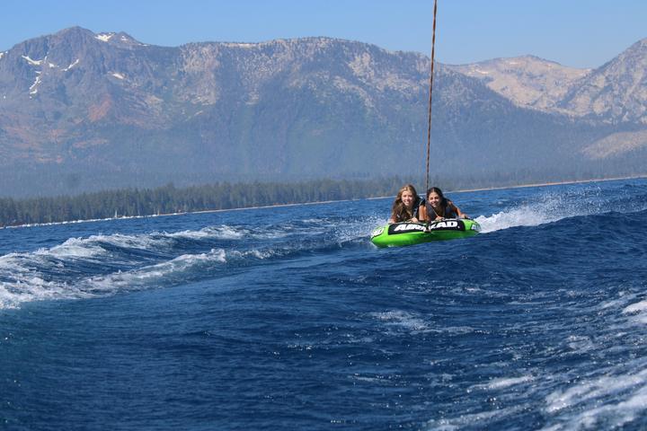 Two teens on a tube being towed across Lake Tahoe