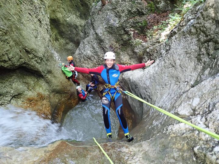 A teen in a wetsuit and helmet canyoning in a rocky gorge in Slovenia
