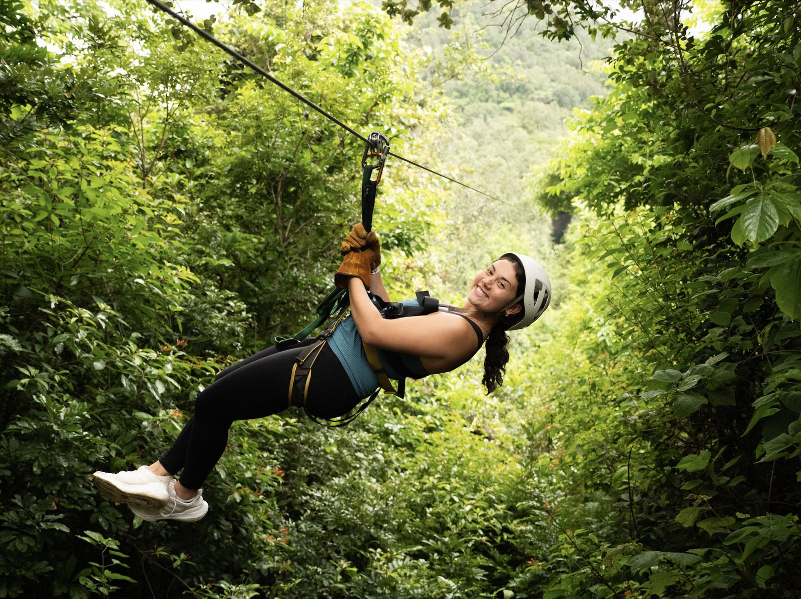A girl smiling as she flies along a zipline through the rainforest