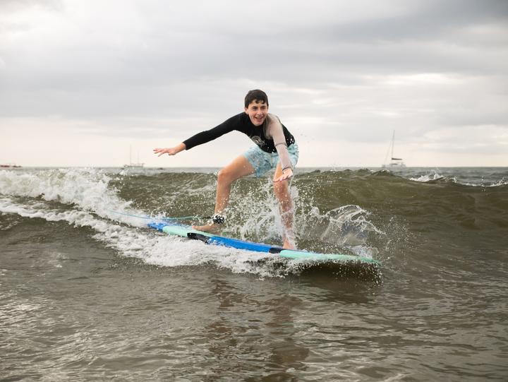 A teen surfing a small wave