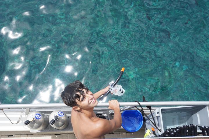 A boy with a snorkel climbing back onto the boat