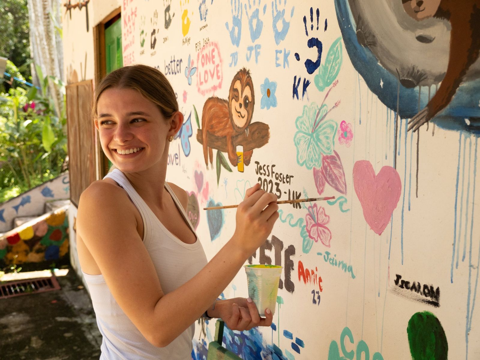 A girl painting a colourful mural on a community wall
