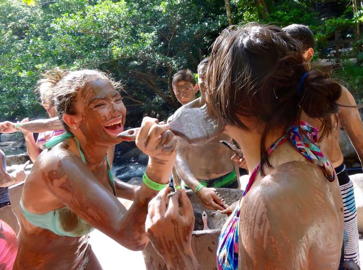 Teens laughing with volcanic mud on their faces
