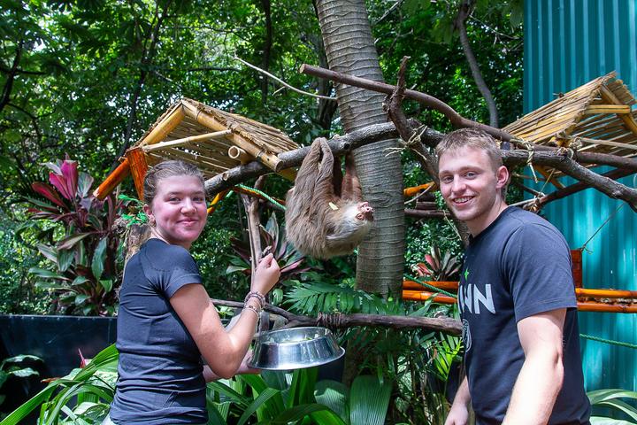 Two teens feeding a sloth at a wildlife rescue centre
