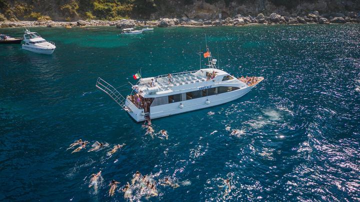 Teens swimming off a private boat in a turquoise bay near Sorrento
