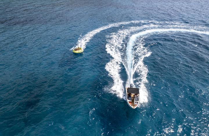 A speedboat towing a tube across the open sea