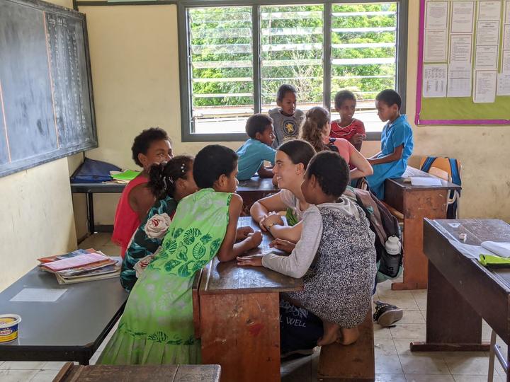 Teens helping pupils with schoolwork in a Fijian classroom