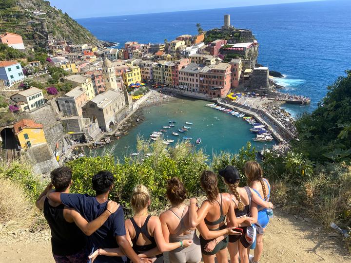 Teens looking down at the colourful harbour village of Vernazza in the Cinque Terre