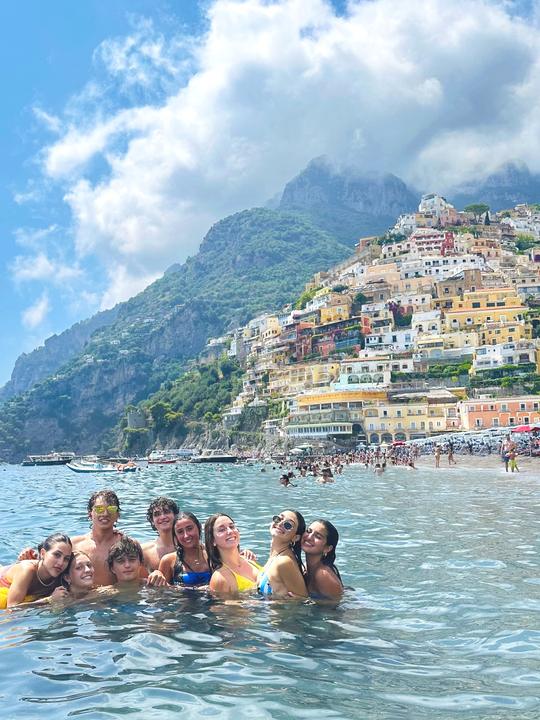 Teens swimming off the beach at Positano, with the town climbing the cliffs behind