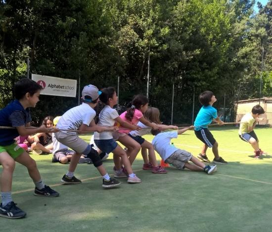 Children pulling hard in a tug-of-war on the pitch