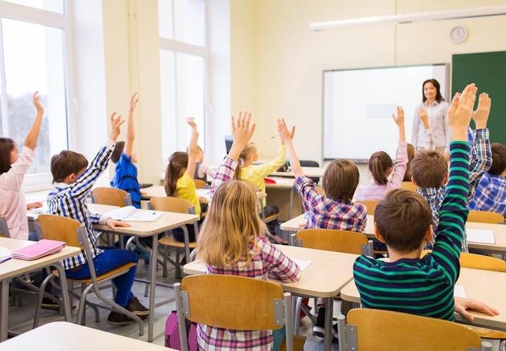 Children raising their hands in an English class