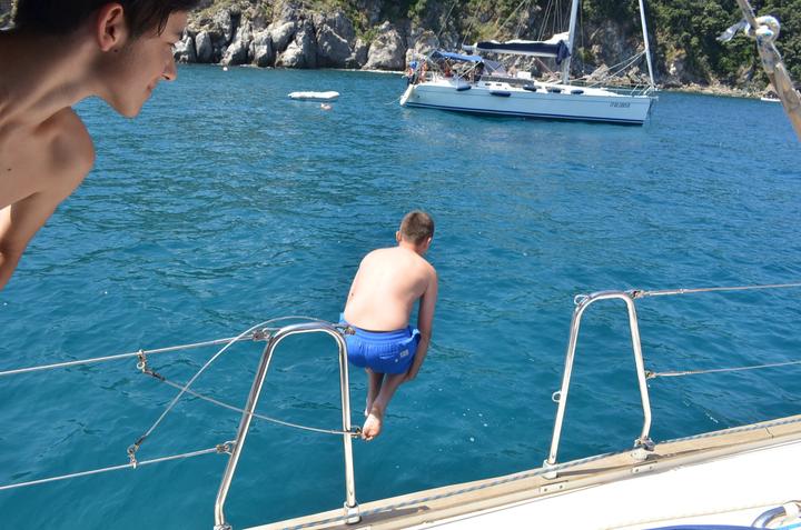 A camper jumping from the yacht into clear blue water