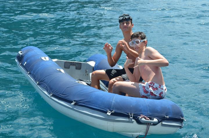 Two boys in the yacht's dinghy in turquoise water