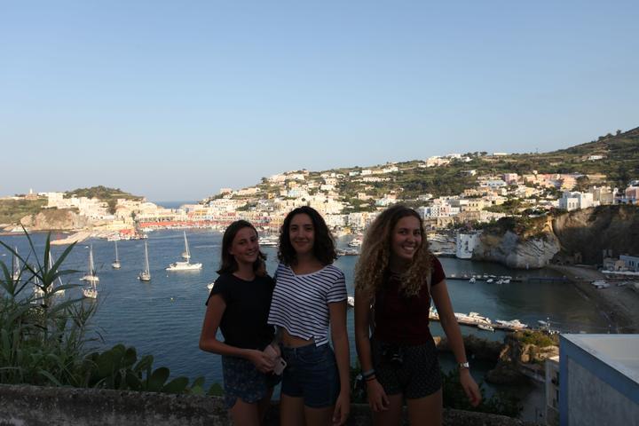 Three girls ashore above a colourful island harbour
