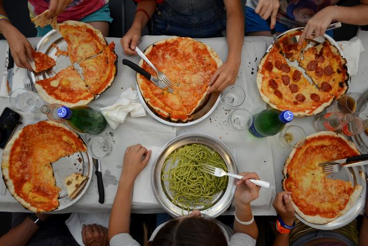 Pizzas and pasta shared around a table, seen from above