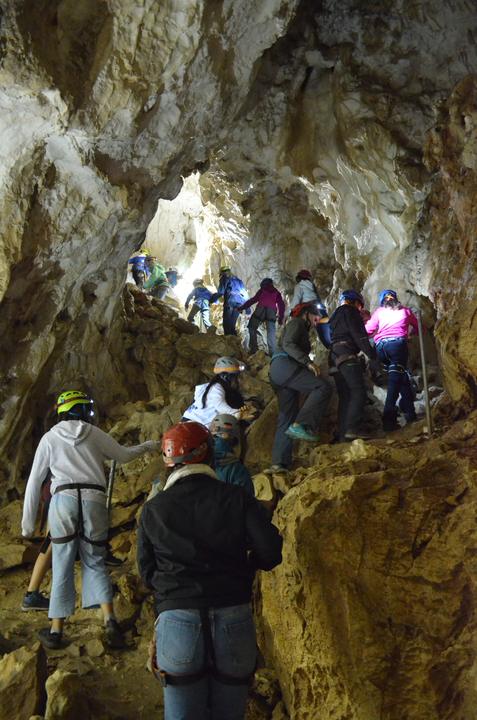Campers with headlamps and helmets inside a cave
