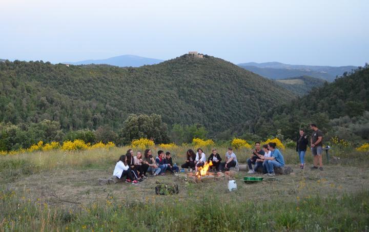 Campers around a campfire in a mountain meadow