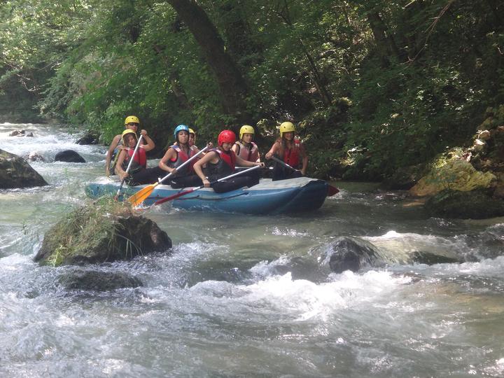 A rafting crew in red helmets on a forest river