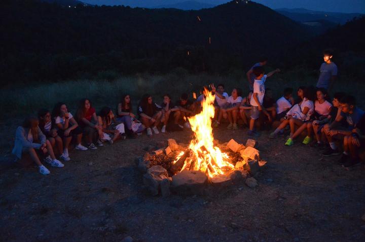 An evening campfire with campers sitting in a circle