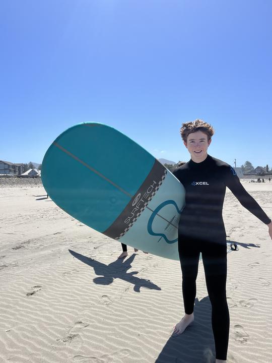 A girl with a surfboard on an Oregon beach