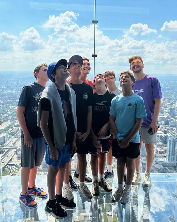 Boys standing on the glass ledge of a Chicago skyscraper