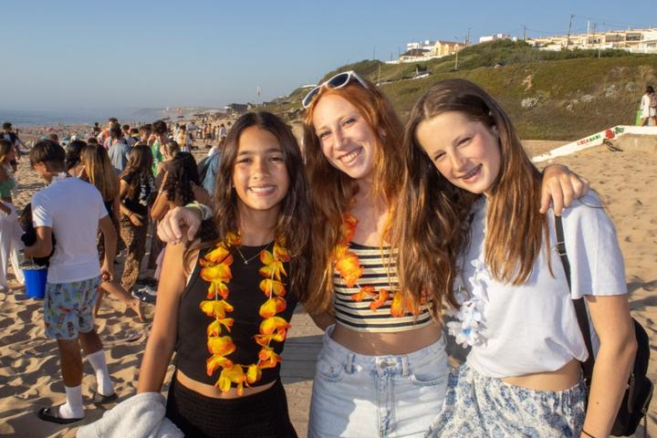 Three campers with flower garlands smiling on the beach at Santa Cruz