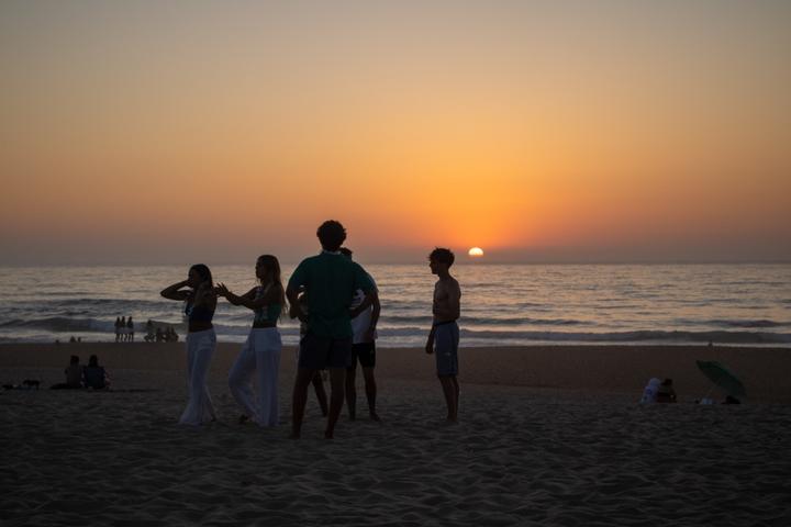 Campers silhouetted against the sunset on the beach