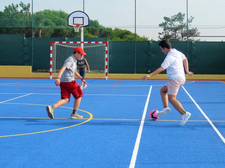 Campers playing football on the residence's outdoor sports court