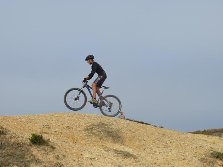 Camper jumping a mountain bike over a sandy ridge