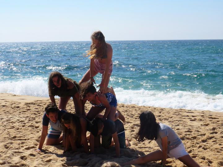 Campers building a human pyramid on the beach