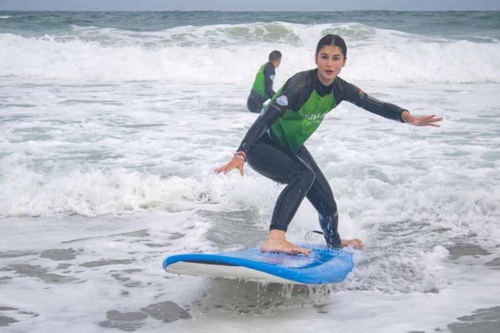 Teen surfer riding a wave in a camp rash guard