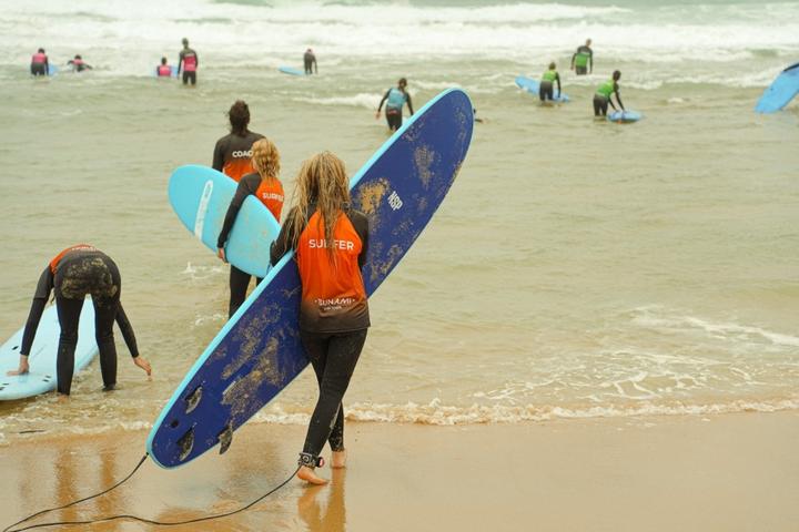 Campers carrying surfboards into the shallow water