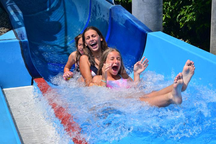 Two campers laughing at the bottom of a water slide at the Aigle water park