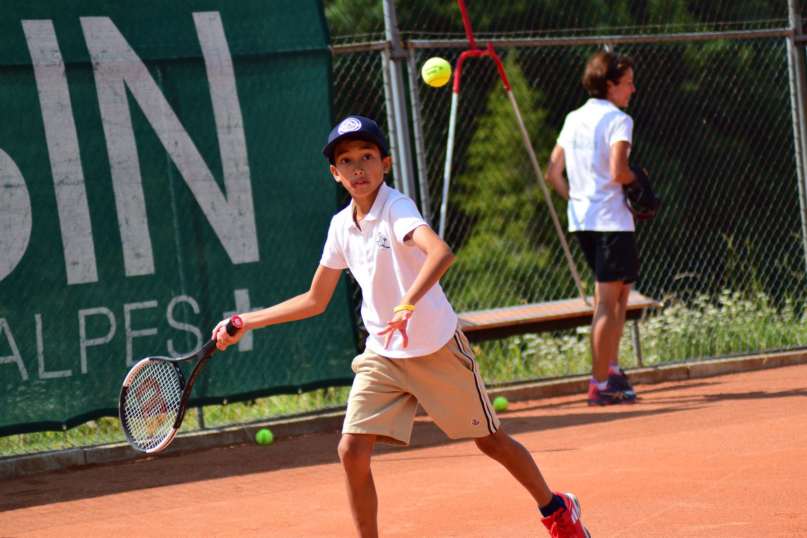 Young player hitting a forehand on a clay court