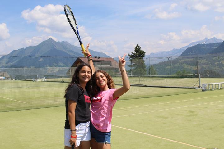 Two campers with rackets on a court with mountain views