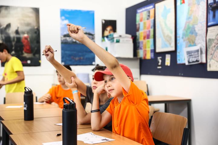 Campers putting their hands up during an English lesson