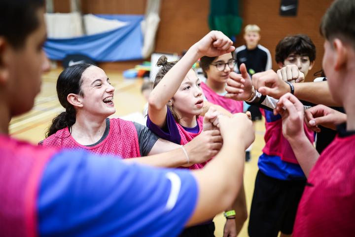 A girls' team cheering and laughing together on court