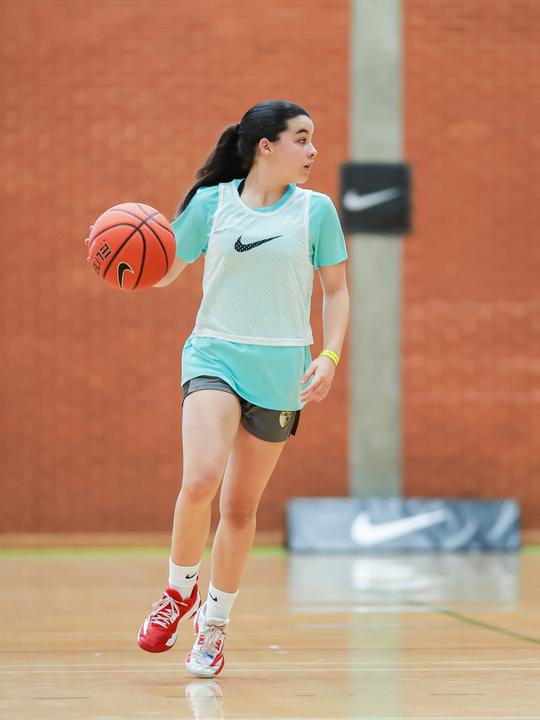 A girl dribbling up the court in a camp game