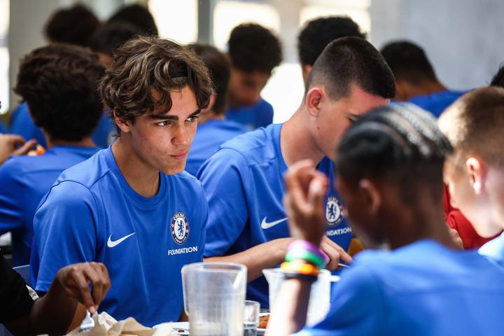 Campers in Chelsea kit eating together in the dining hall