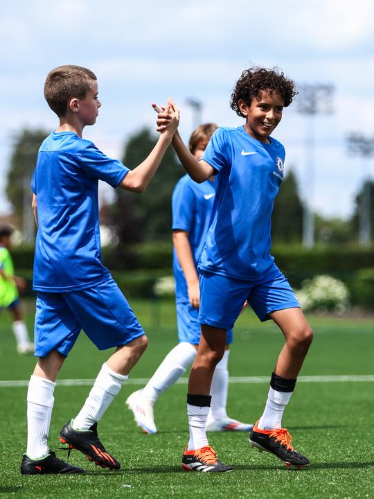 Two young players high-fiving on the training pitch