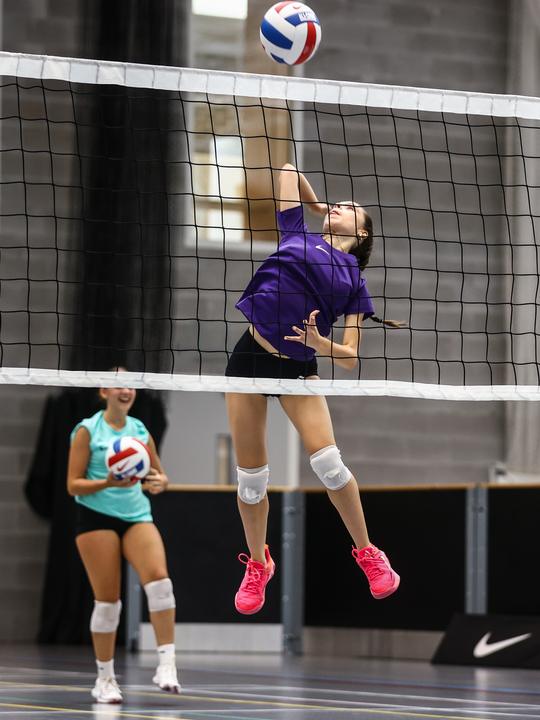 A player jumping to spike at the net