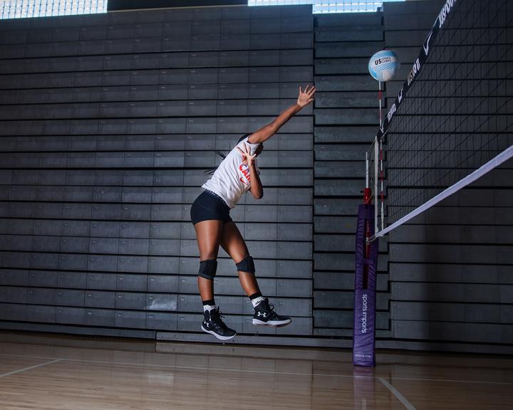 A player reaching high at the net