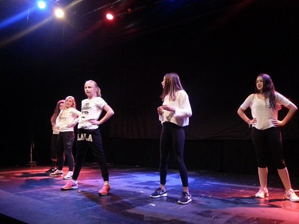 Students dancing on stage under coloured lights