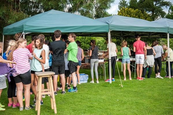 Students at a summer barbecue under gazebos on the lawn