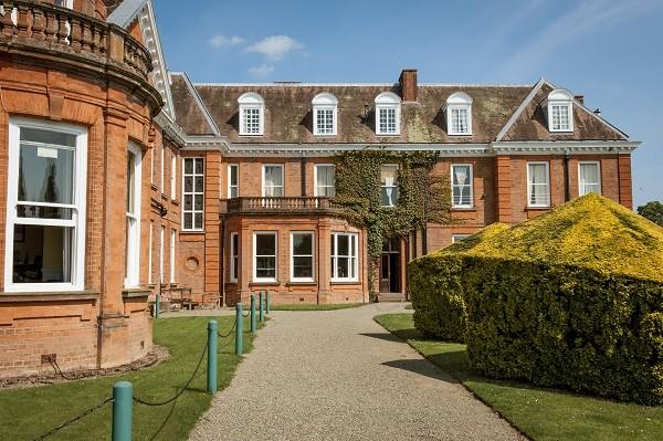 A path between clipped hedges to the school's main building