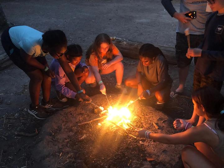 Campers toasting marshmallows round the campfire
